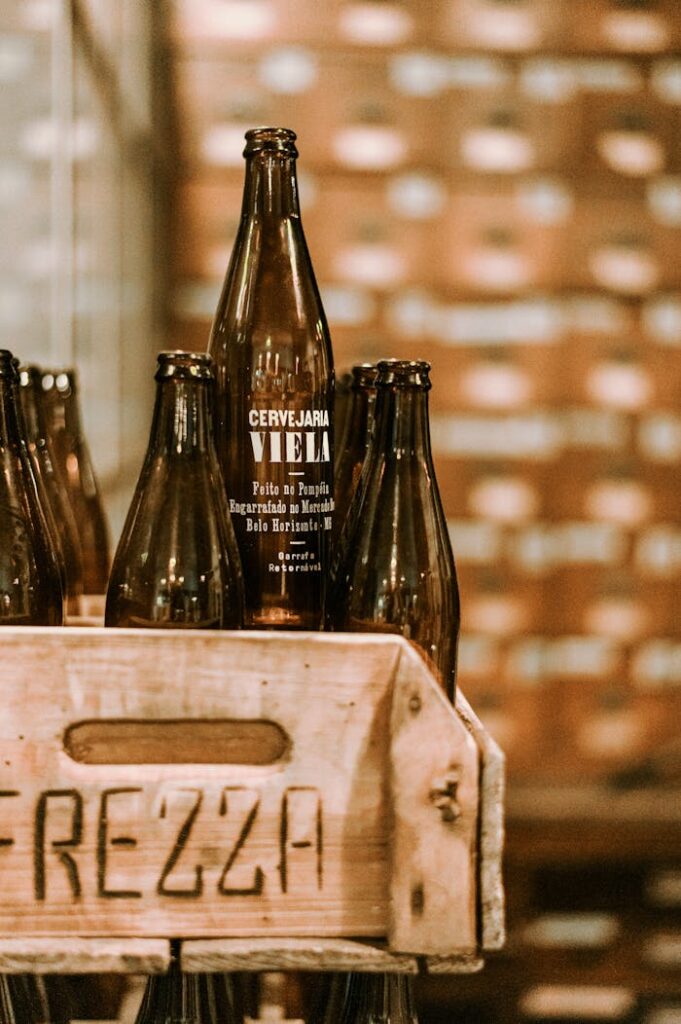 Galerie Close-up of dark glass beer bottles in a wooden crate with a blurred background at a brewery.