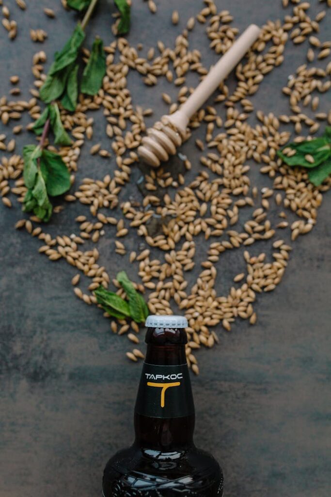 Galerie A vertical shot of a beer bottle surrounded by barley, mint, and a honey dipper.